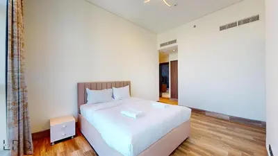 a bedroom with a white bed with a wooden floor at Stunning 2-Bed Apartment with Canal View in Dubai