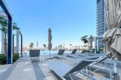 a patio with lounge chairs and a swimming pool at Serene 2BDR with Beach Scenery In Creek Edge- Creek Harbour in Dubai