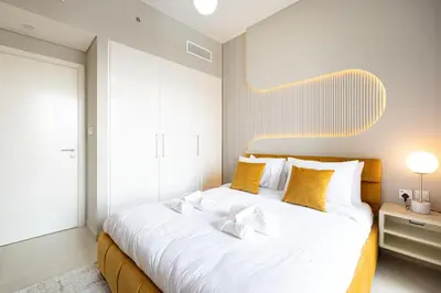 a bedroom with a large white bed with yellow pillows at Downtown Dreams Burj Khalifa View with Dubai Mall, Pool & Free Parking in Dubai