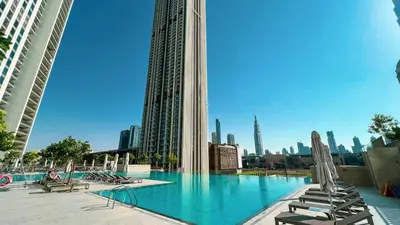 a swimming pool with lounge chairs and a city skyline at Downtown Dreams Burj Khalifa View with Dubai Mall, Pool & Free Parking in Dubai