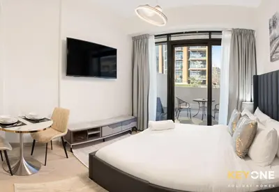 a hotel room with a bed and a desk and a table at Azizi Riviera Studio with Chic Furnishing in Dubai