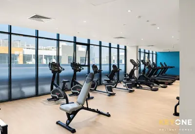 a row of treadmills in a gym with windows at Azizi Riviera Studio with Chic Furnishing in Dubai