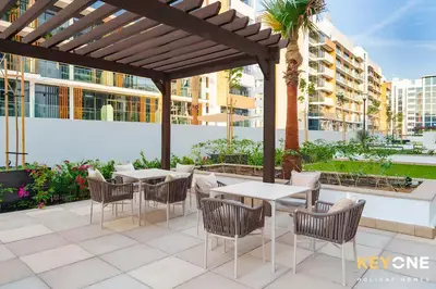 a patio with tables and chairs under a pergola at Azizi Riviera Studio with Chic Furnishing in Dubai