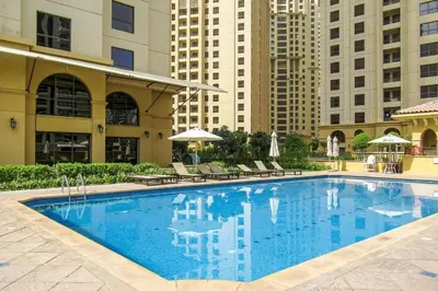 a large swimming pool with chairs and buildings at Spacious bedroom with easy access to the tram and beach, located near JBR Walk in Dubai