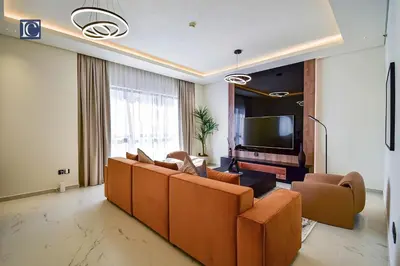 a living room with couches and a flat screen tv at Luxury Escapes - Luxurious 2-Bedroom Apartment with Stunning Lake Views in JBR in Dubai