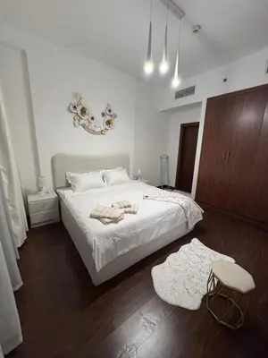 a bedroom with a white bed and a wooden floor at Brand New Apartment IN JVC in Dubai