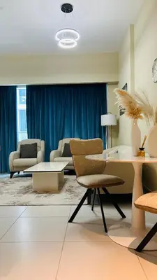a living room with chairs and a table and blue curtains at MontRose Residence Tower A in Dubai