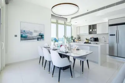 a white kitchen with a dining room table and chairs at Frank Porter - Sunrise Tower in Dubai