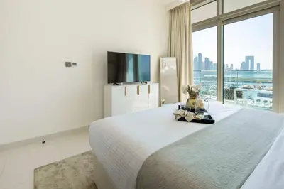 a white bedroom with a large bed and a large window at Frank Porter - Sunrise Tower in Dubai