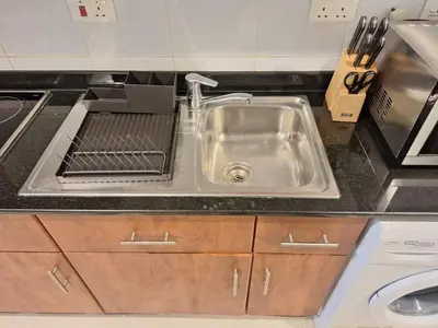 a kitchen sink with a drying rack next to it at Bright Studio Unit at Lake Terrace with lake view in Dubai