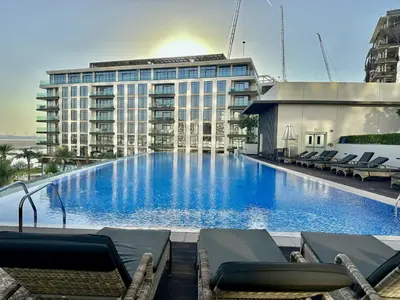 a large swimming pool with lounge chairs in front of a building at NEW Exceptional Lagoon View - 2 Stylish Bedrooms in Dubai