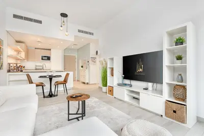 a living room with a white couch and a kitchen at Ahlan HH - Beautiful 1BR Home with Pool View - Belgravia III, JVC in Dubai
