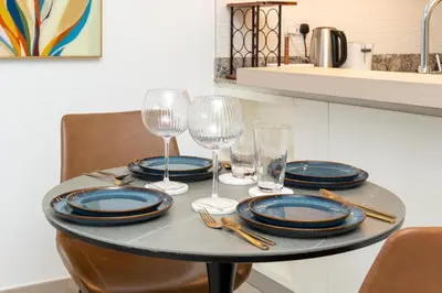 a table with plates and wine glasses on it at Ahlan HH - Beautiful 1BR Home with Pool View - Belgravia III, JVC in Dubai