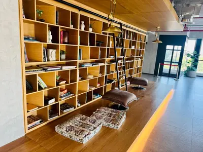 a room with a book shelf with two chairs and a couch at Sunny 1 Bedroom Apartment in Dubai Hills Estate in Dubai