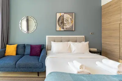 a bedroom with a bed and a blue couch at Cozy Marina Studio with Partial Sea View in Dubai
