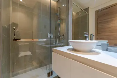 a bathroom with a sink and a glass shower at Cozy Marina Studio with Partial Sea View in Dubai