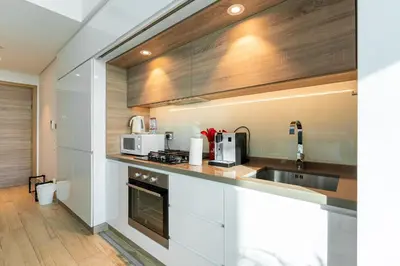 a kitchen with white cabinets and a sink at Cozy Marina Studio with Partial Sea View in Dubai