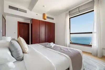 a bedroom with a large white bed with a large window at GuestReady - Enchanting retreat in JBR in Dubai