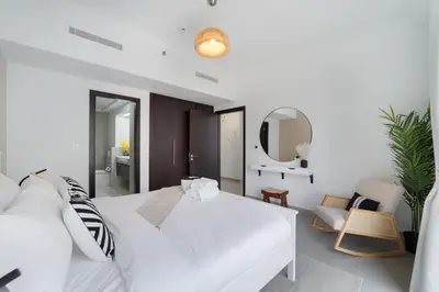 a white bedroom with a large bed and a mirror at HAVN - 1 Bedroom in Downtown, Burj Khalifa View in Dubai