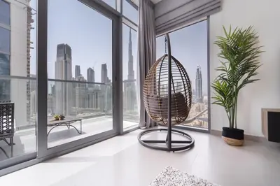 a room with a large window with a rattan chair at HAVN - 1 Bedroom in Downtown, Burj Khalifa View in Dubai