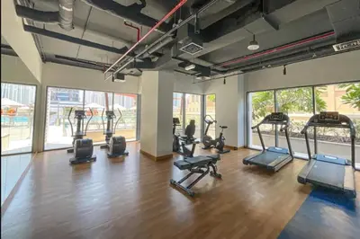 a gym with several treadmills and elliptical machines at HAVN - 1 Bedroom in Downtown, Burj Khalifa View in Dubai