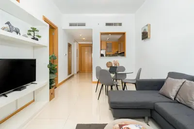 a living room with a couch and a tv at Vacay Lettings - 1 BHK - Iris Blue Dubai Marina in Dubai
