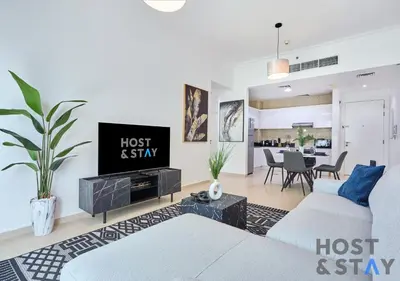 a living room with a couch and a tv at Stylish Renovated 1-Bedroom in Mayfair Residency in Dubai