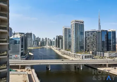 a bridge over a river in a city with tall buildings at Stylish Renovated 1-Bedroom in Mayfair Residency in Dubai