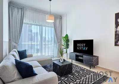 a living room with a couch and a tv at Stylish Renovated 1-Bedroom in Mayfair Residency in Dubai
