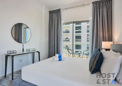 a bedroom with a bed and a large window at Stylish Renovated 1-Bedroom in Mayfair Residency in Dubai