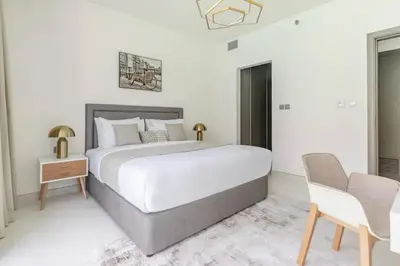 a white bedroom with a large bed and a chair at District one Full Water view Apartment in Dubai