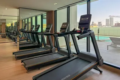 a row of treadmills in a gym at Stylish 1 Bedroom in Binghatti Lavender JVC in Dubai