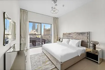 a bedroom with a bed and a large window at 2BR plus Maid Bellevue Tower 1, Burj Khalifa View in Dubai