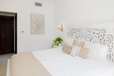 a white bedroom with a large white bed with pillows at 1001 Nights - Luxury 1-BR apartment near Burj in Dubai