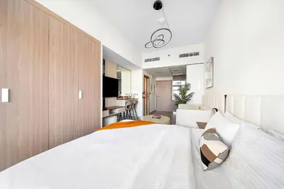 a bedroom with a white bed and a kitchen at Studio Azizi Riviera 35, Community View in Dubai