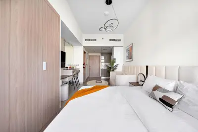 a bedroom with a large white bed and a kitchen at Studio Azizi Riviera 35, Community View in Dubai