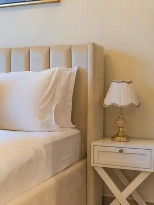a bed with a white pillow and a lamp on a night stand at Tranquil Studio Getaway in Meydan City in Dubai