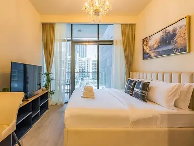 a bedroom with a large white bed and a television at Tranquil Studio Getaway in Meydan City in Dubai