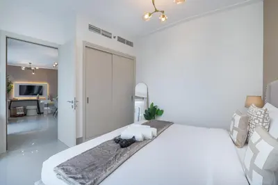 a white bedroom with a bed and a living room at Luxury Apartment in the Heart of Downtown Dubai in Dubai