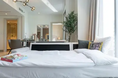 a white bed with a book on top of it at Luxury Apartment in the Heart of Downtown Dubai in Dubai