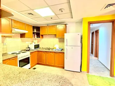 a kitchen with wooden cabinets and a white refrigerator at Private Rooms in CoLiving Apartments UP Tower DIFC in Dubai