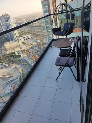 a balcony with a table and chairs on a skyscraper at Cozy Golf & Lake View 1BR Apartment,Damac Hills 1 in Dubai