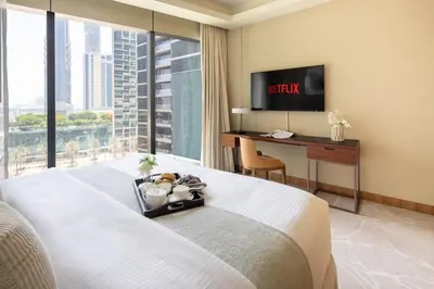 a hotel room with a bed with a desk and a television at Frank Porter - Address Opera in Dubai