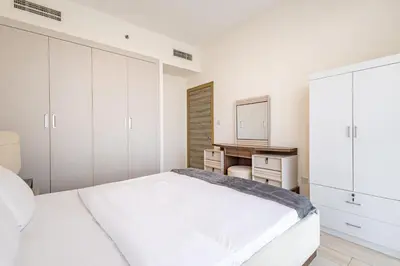 a white bedroom with a bed and a desk at Superhost - Bright & Stylish 1-Bedroom in Bloom Tower, JVC in Dubai