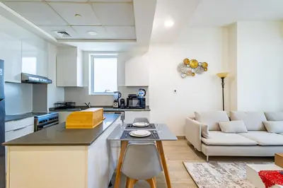 a kitchen and living room with a couch and a table at Superhost - Bright & Stylish 1-Bedroom in Bloom Tower, JVC in Dubai