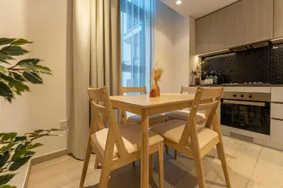 a kitchen with a wooden table and chairs at HAVN - 1 Bedroom in Harrington House, JVC in Dubai