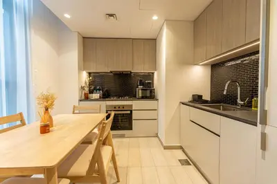 a kitchen with a wooden table and a dining room at HAVN - 1 Bedroom in Harrington House, JVC in Dubai