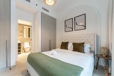 a bedroom with a white bed with a green blanket at HAVN - 1 Bedroom in Harrington House, JVC in Dubai