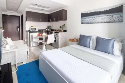 a bedroom with a large bed and a kitchen at Frank Porter - Hanover Square in Dubai