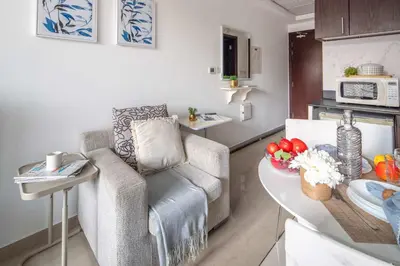 a living room with a chair and a table in a kitchen at Frank Porter - Hanover Square in Dubai